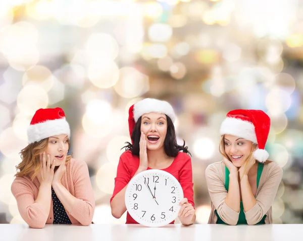 Usmívající se ženy v santa hat pomocníka s hodinami — Stock fotografie