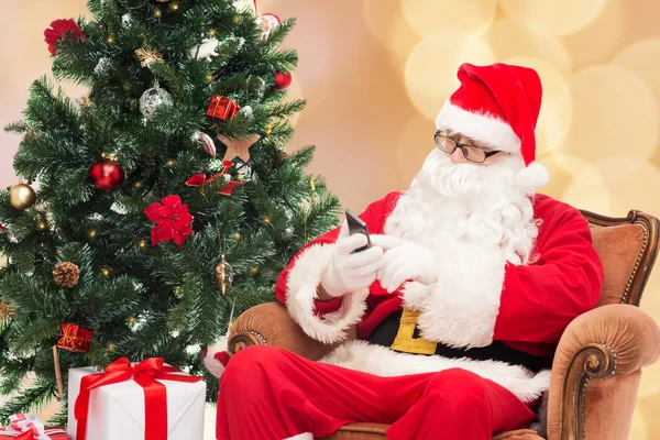 Santa claus with smartphone and christmas tree — Stock Photo, Image