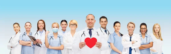 Grupa uśmiechający się lekarze z czerwonym sercem kształt — Zdjęcie stockowe