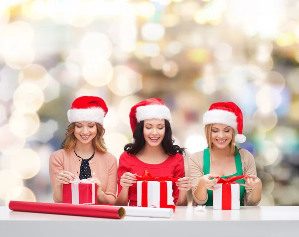 Donne sorridenti in cappelli Babbo Natale helper imballaggio regali Foto Stock