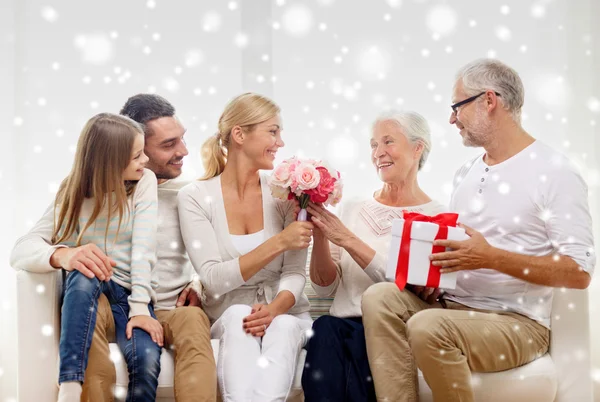 Famille heureuse avec bouquet et boîte cadeau à la maison — Photo