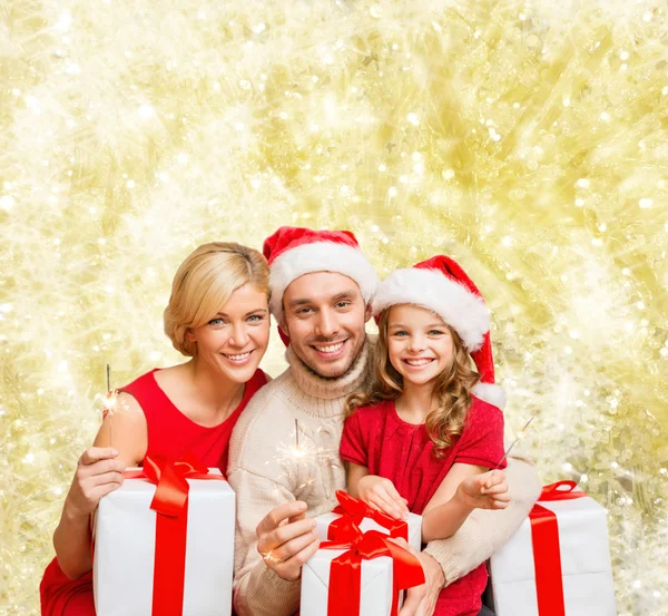 Happy family in santa helper hats with gift boxes — Stock Photo, Image