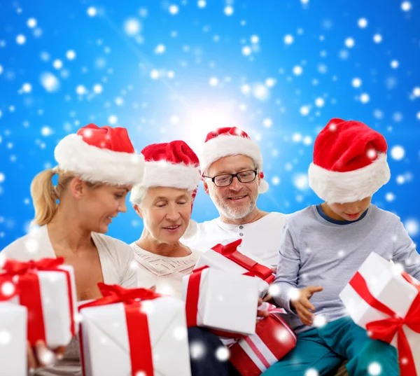Happy family in santa helper hats with gift boxes — Stock Photo, Image