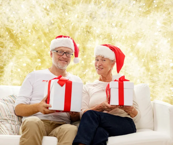 Felice coppia di anziani in cappelli di Babbo Natale con scatole regalo — Foto Stock