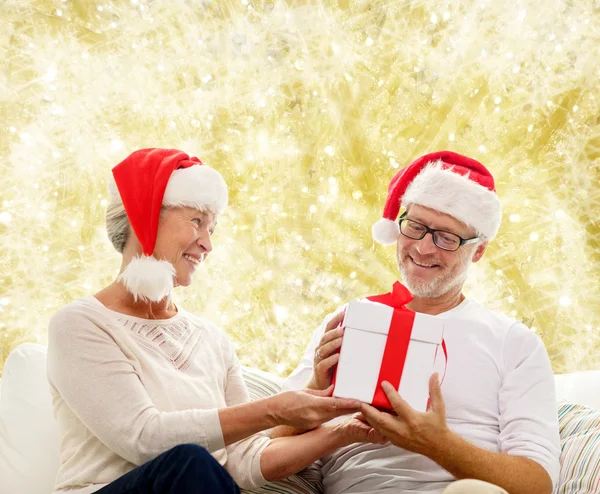 Glückliches Seniorenpaar in Weihnachtsmützen mit Geschenkbox — Stockfoto