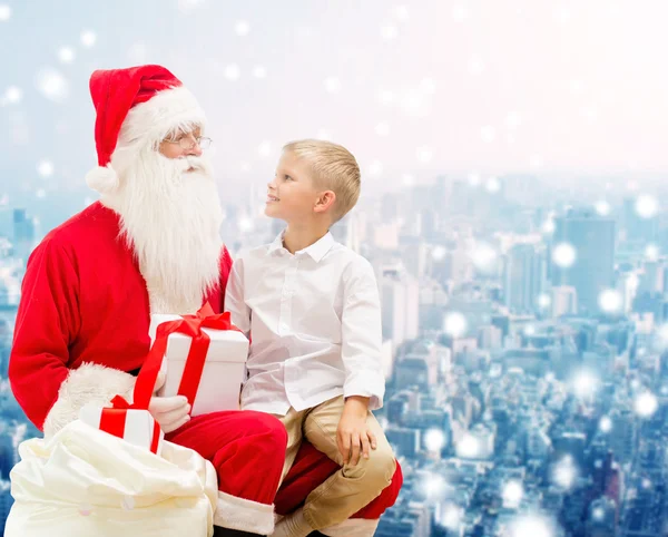 Petit garçon souriant avec santa claus et cadeaux — Photo