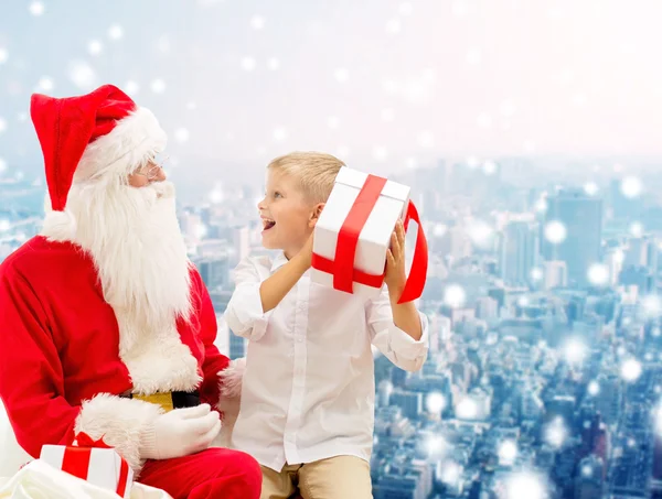 Petit garçon souriant avec santa claus et cadeaux — Photo