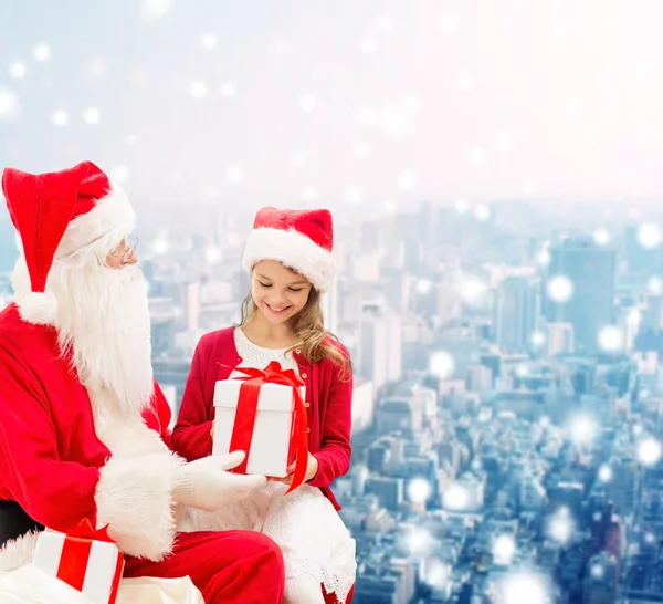 Lächelndes kleines Mädchen mit Weihnachtsmann und Geschenken — Stockfoto