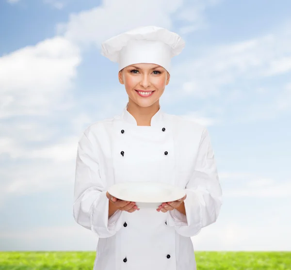 Lachende vrouwelijke chef-kok met lege plaat — Stockfoto