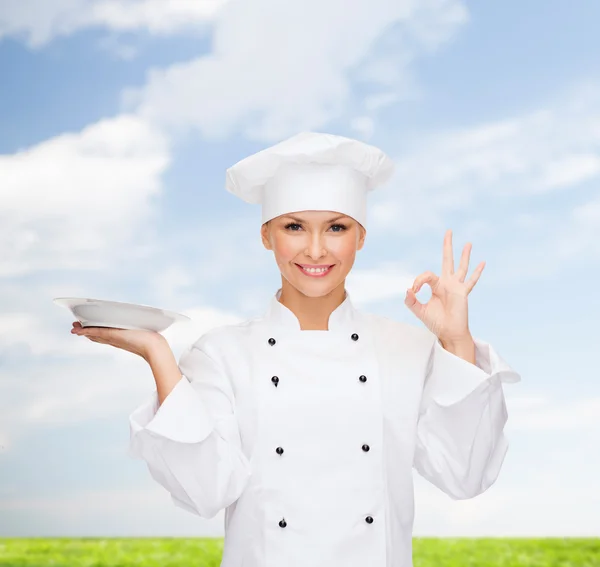 Sorridente chef feminino com placa mostrando sinal ok — Fotografia de Stock