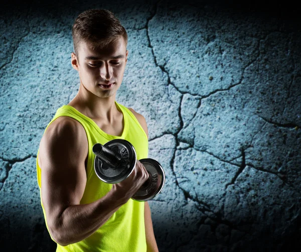 Young man with dumbbell flexing biceps — Stock Photo, Image