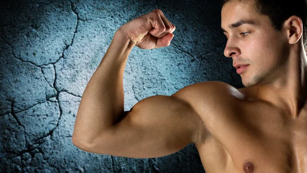 Close up of young man flexing and showing biceps — Stock Photo, Image