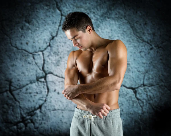 Young male bodybuilder injured touching elbow — Stock Photo, Image