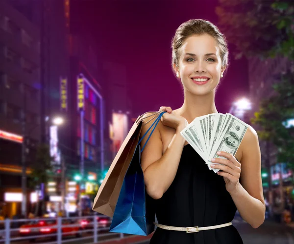 Smiling woman with shopping bags and money — Stock Photo, Image