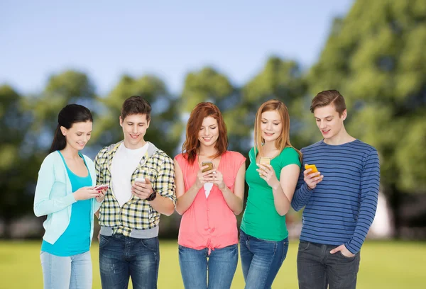 Estudantes sorridentes com smartphones — Fotografia de Stock