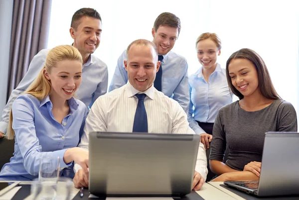 Glimlachende zakenmensen met laptop op kantoor Rechtenvrije Stockfoto's