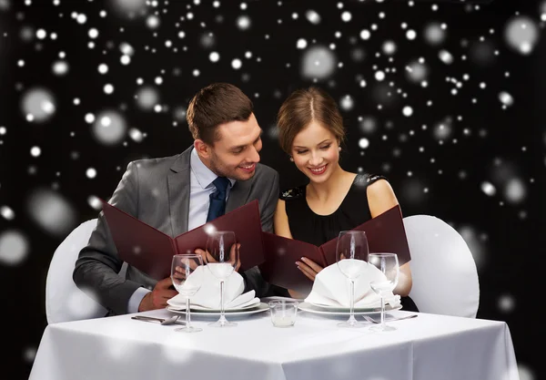 Smiling couple with menus at restaurant — Stock Photo, Image