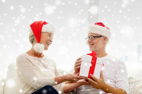 Happy senior couple in santa hats with gift box — Stock Photo, Image