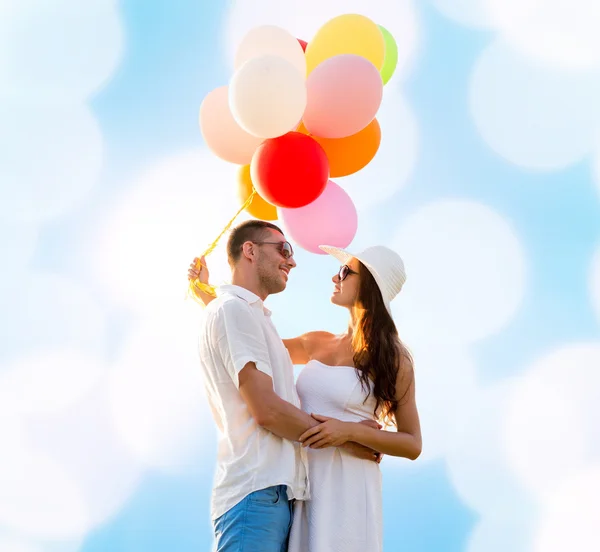 Smiling couple with air balloons outdoors — Stock Photo, Image