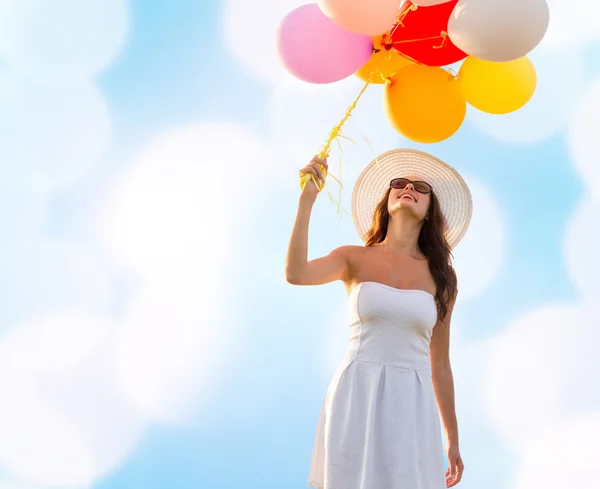 Usměvavá mladá žena v sluneční brýle s balónky — Stock fotografie