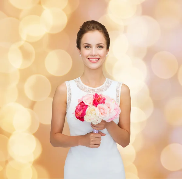 Mulher sorridente em vestido branco com buquê de rosas — Fotografia de Stock