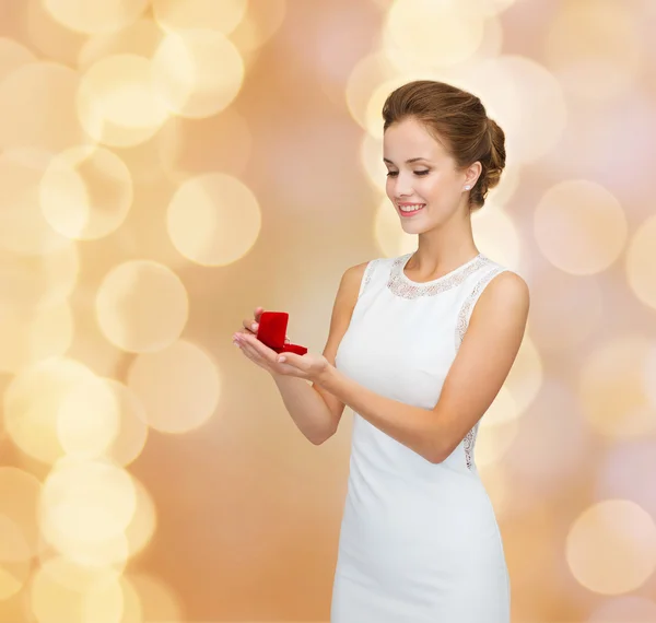 Smiling woman holding red gift box with ring — Stock Photo, Image