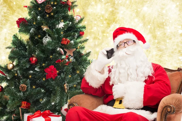 Kerstman met smartphone en kerstboom — Stockfoto
