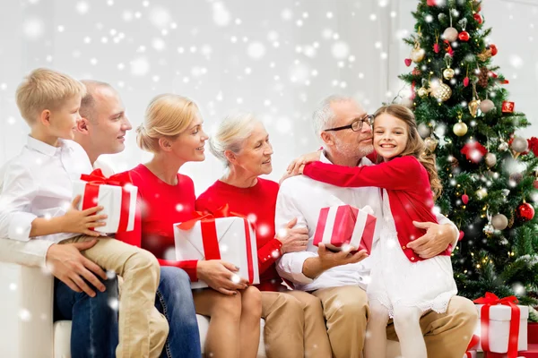 Улыбающаяся семья с подарками, обнимающими дом — стоковое фото