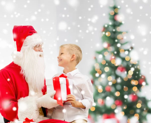 Niño sonriente con santa claus y regalos — Foto de Stock