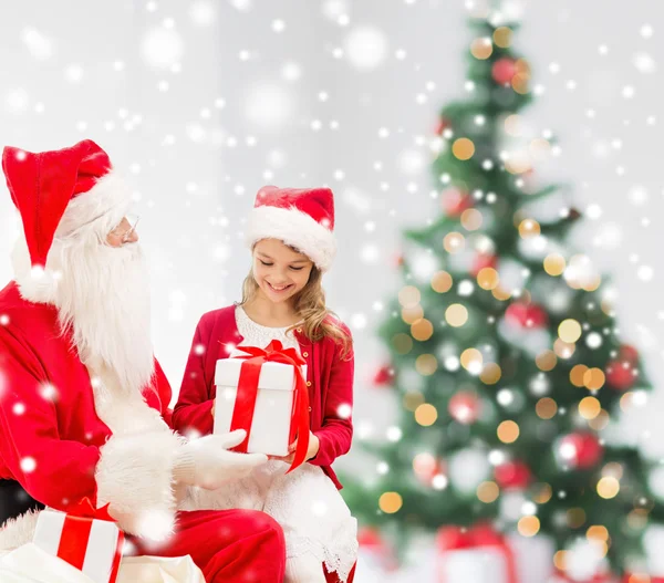 Niña sonriente con santa claus y regalos — Foto de Stock