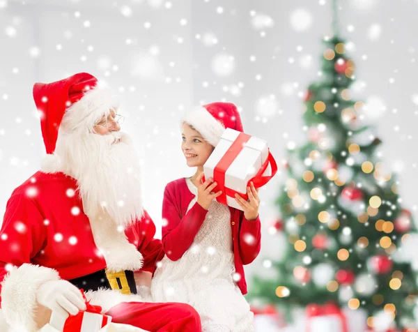 Lächelndes kleines Mädchen mit Weihnachtsmann und Geschenken — Stockfoto