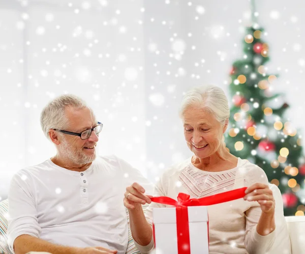 Happy senior couple with gift box at home — Stock Photo, Image