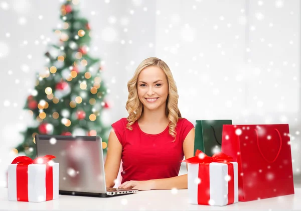 Vrouw met geschenkdozen en laptopcomputer — Stockfoto