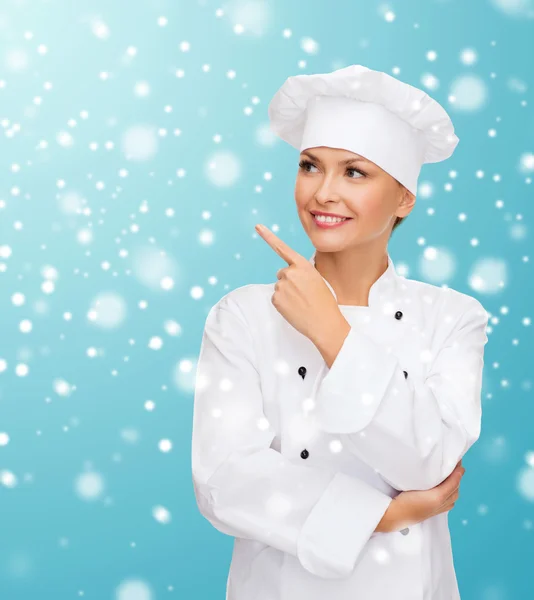 Sonriente cocinera soñando apuntando con el dedo hacia arriba — Foto de Stock