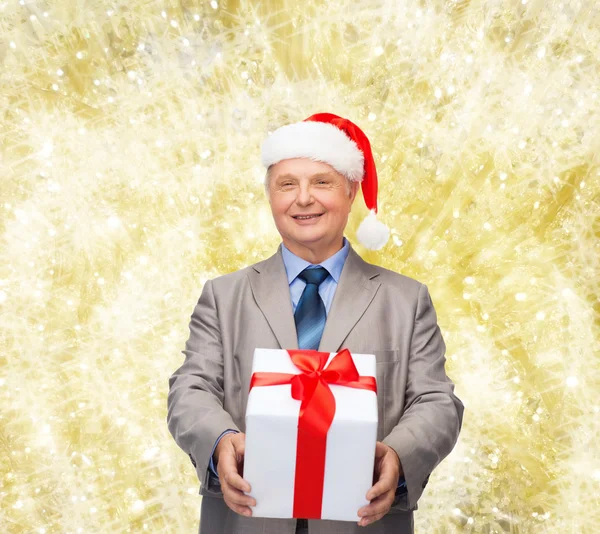 Sorrindo homem de terno e chapéu de Papai Noel ajudante com presente — Fotografia de Stock