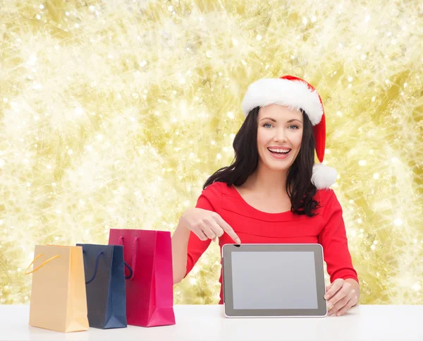 Leende kvinna i santa mössa med väskor och TabletPC — Stockfoto