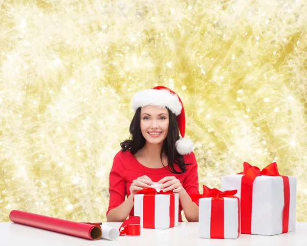 Usmívající se žena v santa čepice pomocníka na balení dárků — Stock fotografie