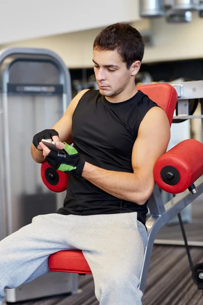 Jeune homme avec smartphone en salle de gym — Photo
