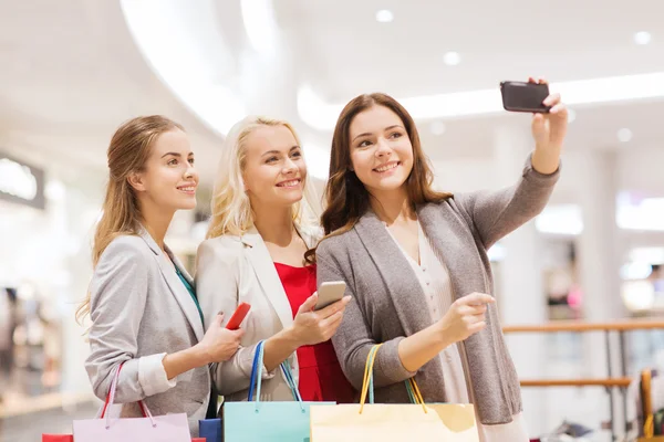 Mujeres con smartphones comprando y tomando selfie —  Fotos de Stock