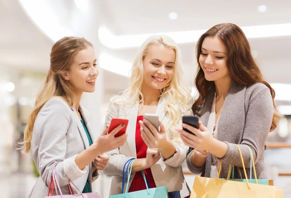 Gelukkig vrouwen met smartphones en shopping tassen — Stockfoto