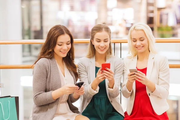 Szczęśliwe kobiety z smartfonów i torby na zakupy — Zdjęcie stockowe