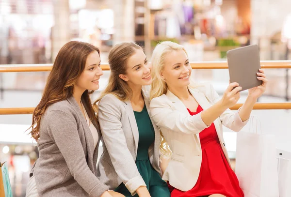 Mujeres jóvenes felices con tableta pc y bolsas de compras —  Fotos de Stock