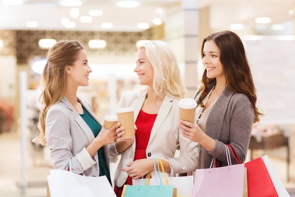 Mulheres jovens com sacos de compras e café no shopping — Fotografia de Stock