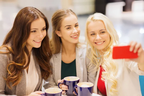 Smiling young women with cups and smartphone — Stock Photo, Image