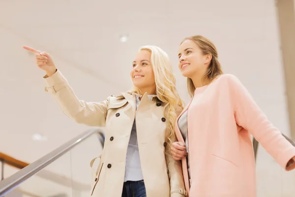 Young women pointing finger on escalator in mall — Stock Photo, Image
