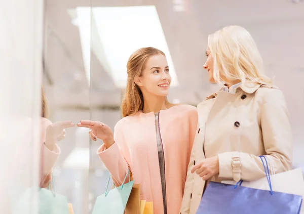 Gelukkig jonge vrouwen met boodschappentassen in winkelcentrum — Stockfoto