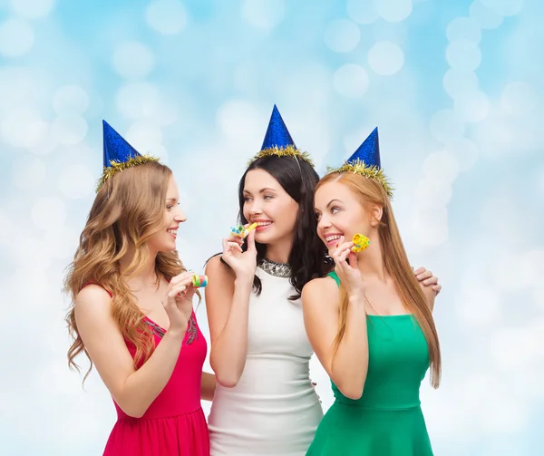 Donne sorridenti in berretti festa che soffiano a fischietti — Foto Stock