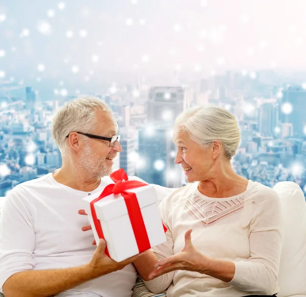 Feliz pareja de ancianos con caja de regalo en casa — Foto de Stock
