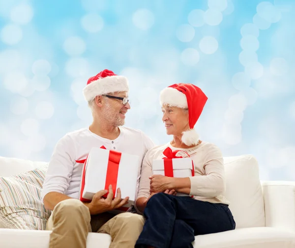 Feliz pareja de ancianos en sombreros de santa con cajas de regalo — Foto de Stock