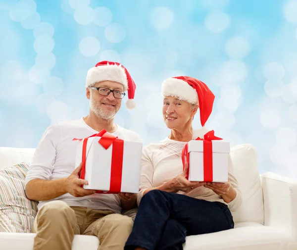 Feliz pareja de ancianos en sombreros de santa con cajas de regalo — Foto de Stock